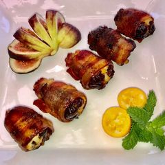 A picture of Bacon wrapped dates stuffed with ricotta cheese.