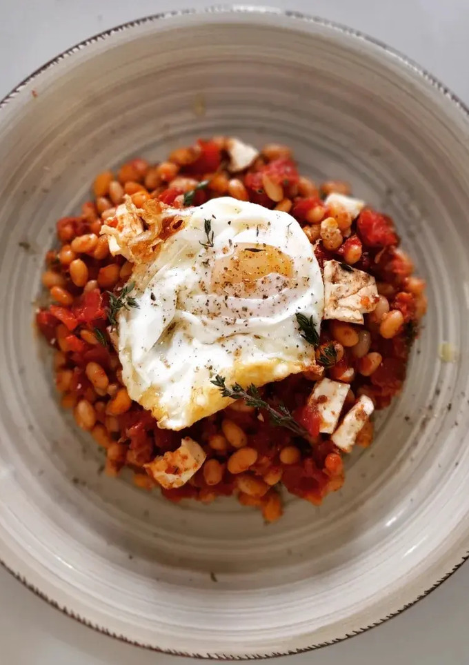 Una foto de Fessolets con tomate y queso feta al horno con huevo frito