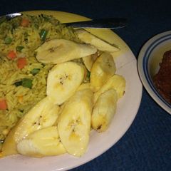 A picture of Fried rice, plantain with peppered meat.
