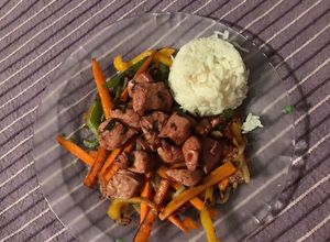 Una foto de Pollo sofrito en vino tinto en colchón de vegetales y timbal de arroz (sin sal)