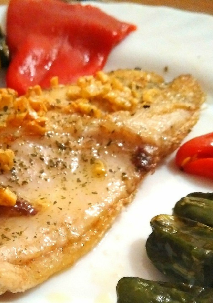 Una foto de Lubina plancha con crujiente de ajo padrón y piquillo