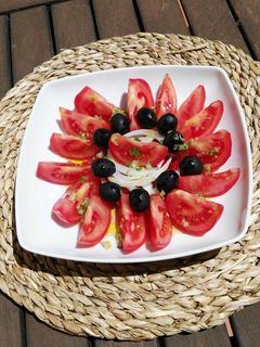 Una foto de Ensalada de tomate, pimientos asados, cebolla y aceitunas