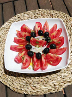 Una foto de Ensalada de tomate, pimientos asados, cebolla y aceitunas