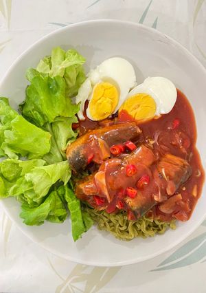 A picture of Spicy canned mackerel in tomato sauce on green noodles.
