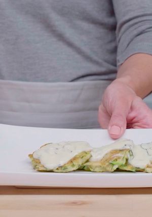 A picture of Zucchini fritters with yogurt sauce.