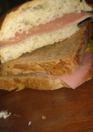 Una foto de Sándwich de mortadela, queso y aderezos