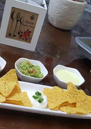 A picture of Cheese nachos with salsa and guacamole.