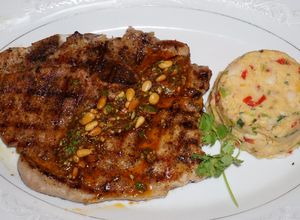 Una foto de Chuletas de cerdo grilladas con chimichurri de piñonesy timbal de porotos blancos