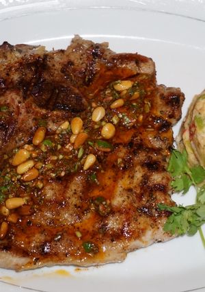 A picture of Grilled Pork Chops with Pine Nut Chimichurri and White Bean Timbale.