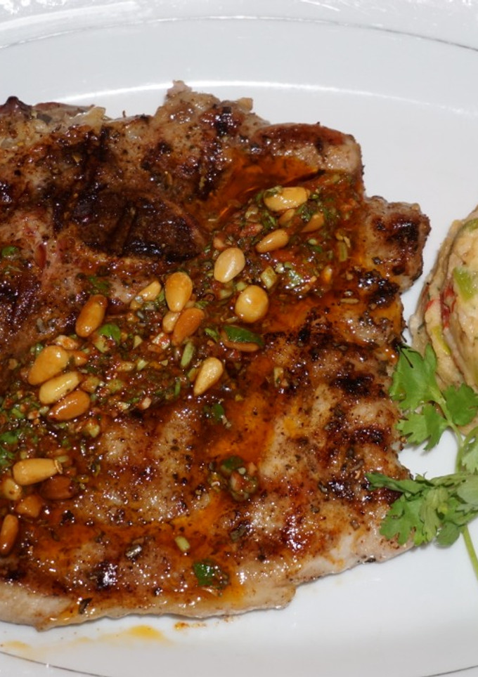 Una foto de Chuletas de cerdo grilladas con chimichurri de piñonesy timbal de porotos blancos