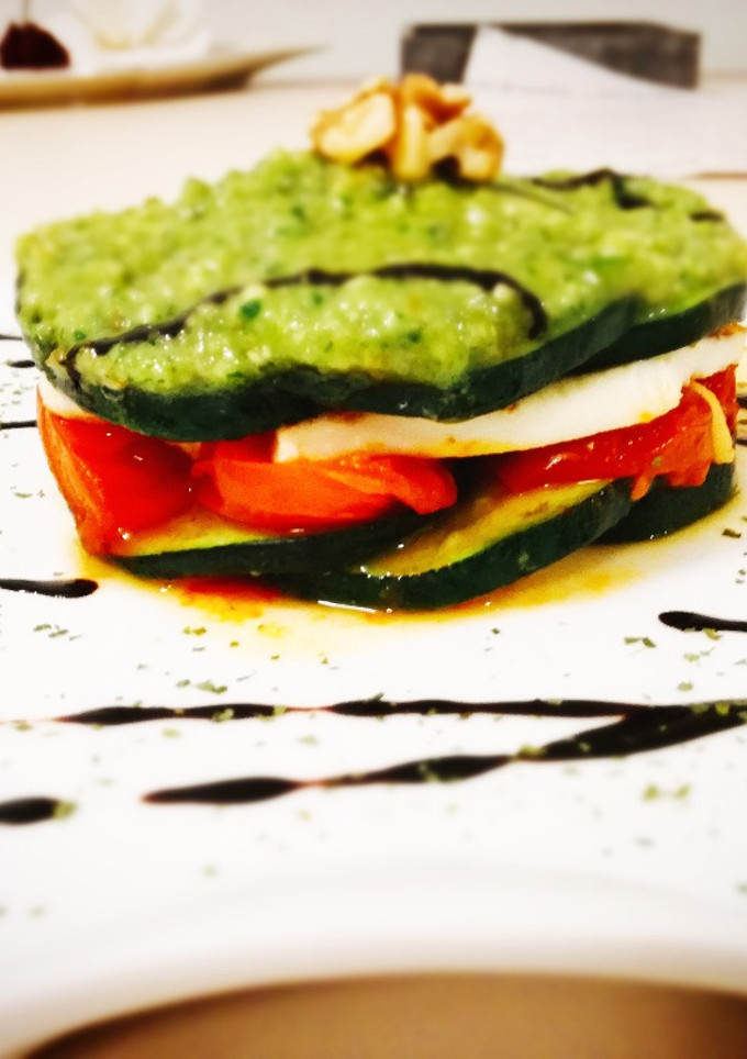 Una foto de Milhojas de calabacín, tomates cherry, queso fresco y pesto de rúcula, queso manchego y nueces
