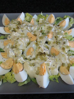 Una foto de Huevos cocidos sobre hojas de ensalada bañados con mayonesa y pepinillos
