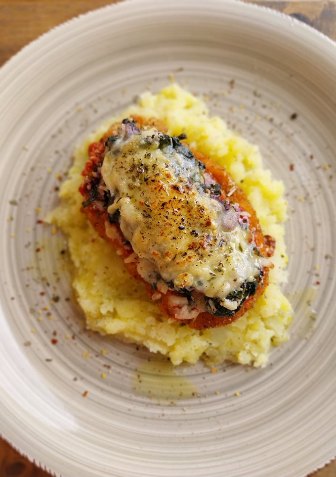 Una foto de Pollo a la parmesana con espinacas y olivas kalamata