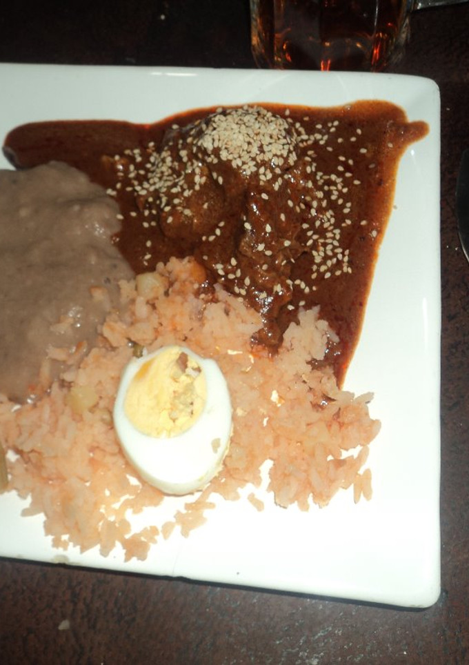Una foto de Mole de nuez ranchero para fiesta con frijoles enchilados y arroz con huevos duros