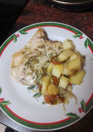 Una foto de Lubina al horno sobre cama de cebolla, papas y tomates cherry