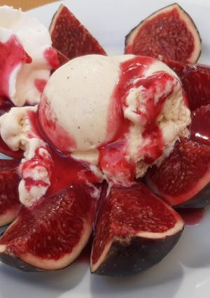 A picture of Figs and Raspberry Coulis with Ice Cream and Cream.