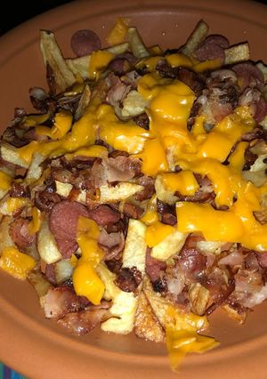Una foto de Salchipapas con panceta y cheddar