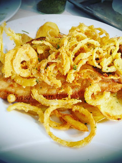 Una foto de Gallo frito sobre cama de patatas y ajo con aros de cebolla🍤🍤