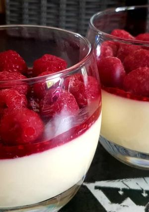 Une photo de Panna cotta vanille avec coulis et framboises 💕