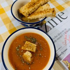 A picture of Carrot Tomato Soup with Bread sticks.