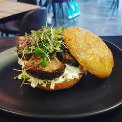 A picture of Herb crusted pork fillet and coleslaw on a bun.