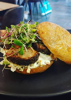 A picture of Herb crusted pork fillet and coleslaw on a bun.