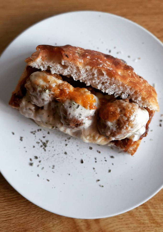 Una foto de Focaccia con albóndigas, cebolla caramelizada y queso gratinado