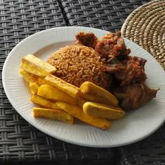 A picture of Jollof rice with fried yam and peppered meat.
