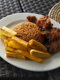 A picture of Jollof rice with fried yam and peppered meat.