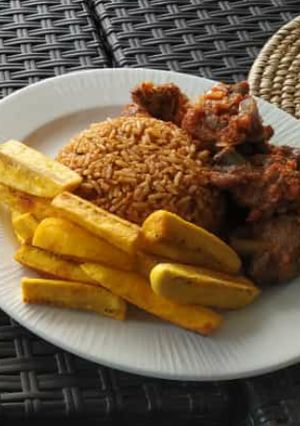 A picture of Jollof rice with fried yam and peppered meat.