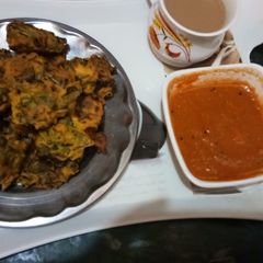 A picture of Palak bhajiye with tea or tomato chutney.