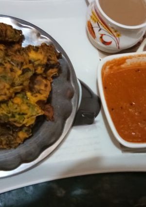 A picture of Palak bhajiye with tea or tomato chutney.