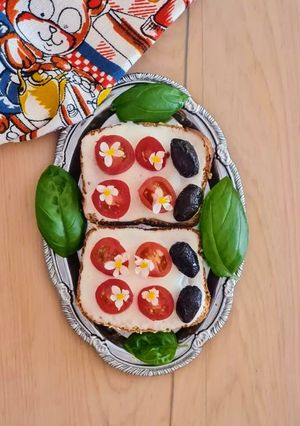 Una foto de Tostas de tomates cherry, albahaca, aceitunas y flores 🥗