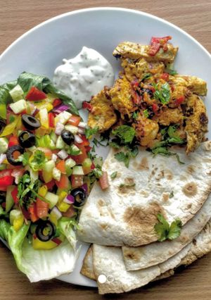 A picture of Chicken tikka kebabs with Indian salad.