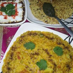 A picture of Daliya khichdi with curd,papad and chutney.