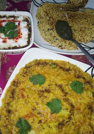 A picture of Daliya khichdi with curd,papad and chutney.