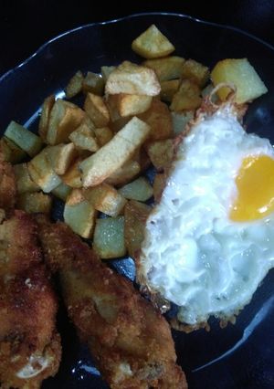 Una foto de Pollo rebozado con papa y huevos fritos