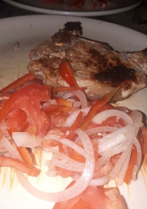 Una foto de Costillas de cerdo con ensalada de tomates, cebolla