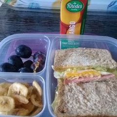 A picture of Egg sandwiches banana chips and grapes.