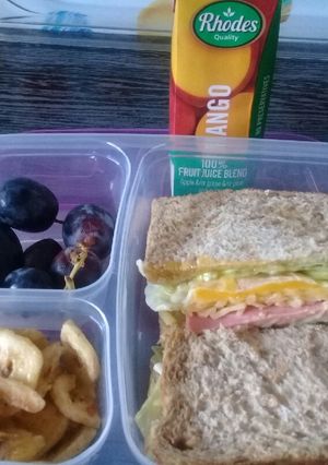 A picture of Egg sandwiches banana chips and grapes.