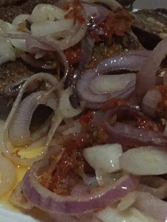 A picture of Fried Tilapia fish with onion sauce.