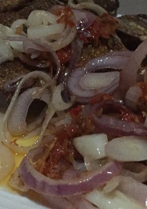 A picture of Fried Tilapia fish with onion sauce.