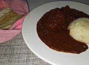 Una foto de Mole Oaxaqueño con pollo y tortillas de maíz hechas a mano