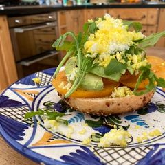 A picture of Tomato and avocado on toasted bagel with grated egg.