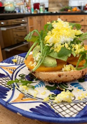 A picture of Tomato and avocado on toasted bagel with grated egg.