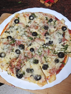 Una foto de Pizza de espinacas, cebolla, bacon y aceitunas negras