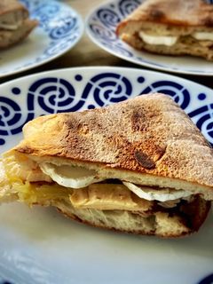 Una foto de Bocadillo caliente de rulo cabra con bonito y cebolla caramelizada