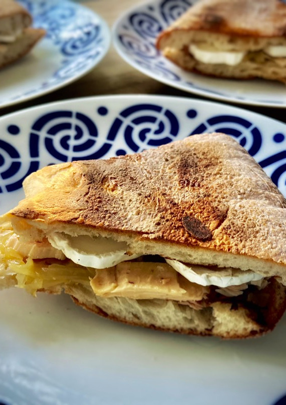 Una foto de Bocadillo caliente de rulo cabra con bonito y cebolla caramelizada