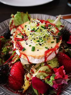 Una foto de Ensalada con frutas, flores y queso de cabra