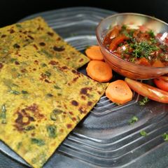 A picture of Methi ka paratha with tomato chutney.